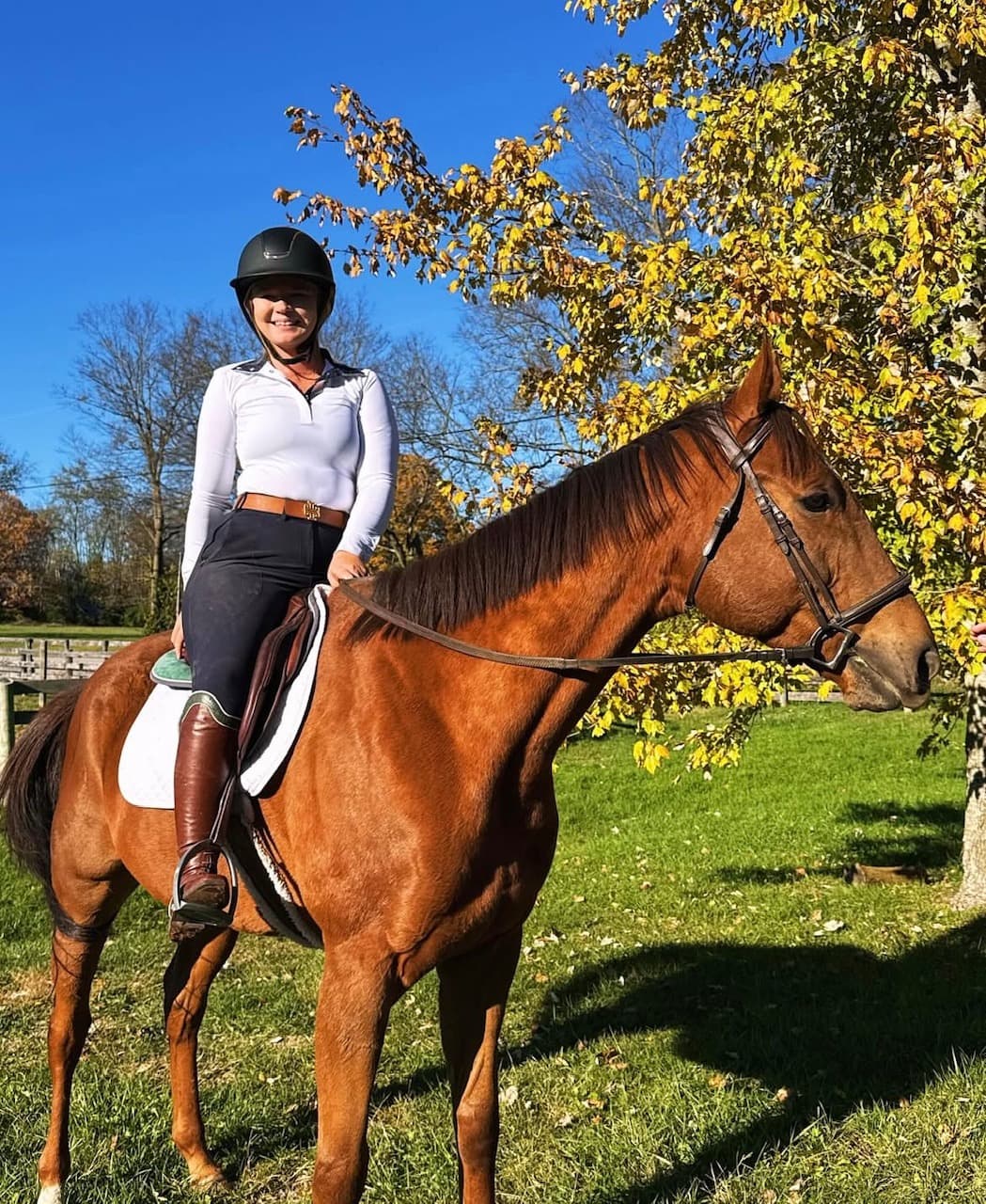 Mackenzie sitting on Biggie, an off-the-track Thoroughbred, under autumn leaves